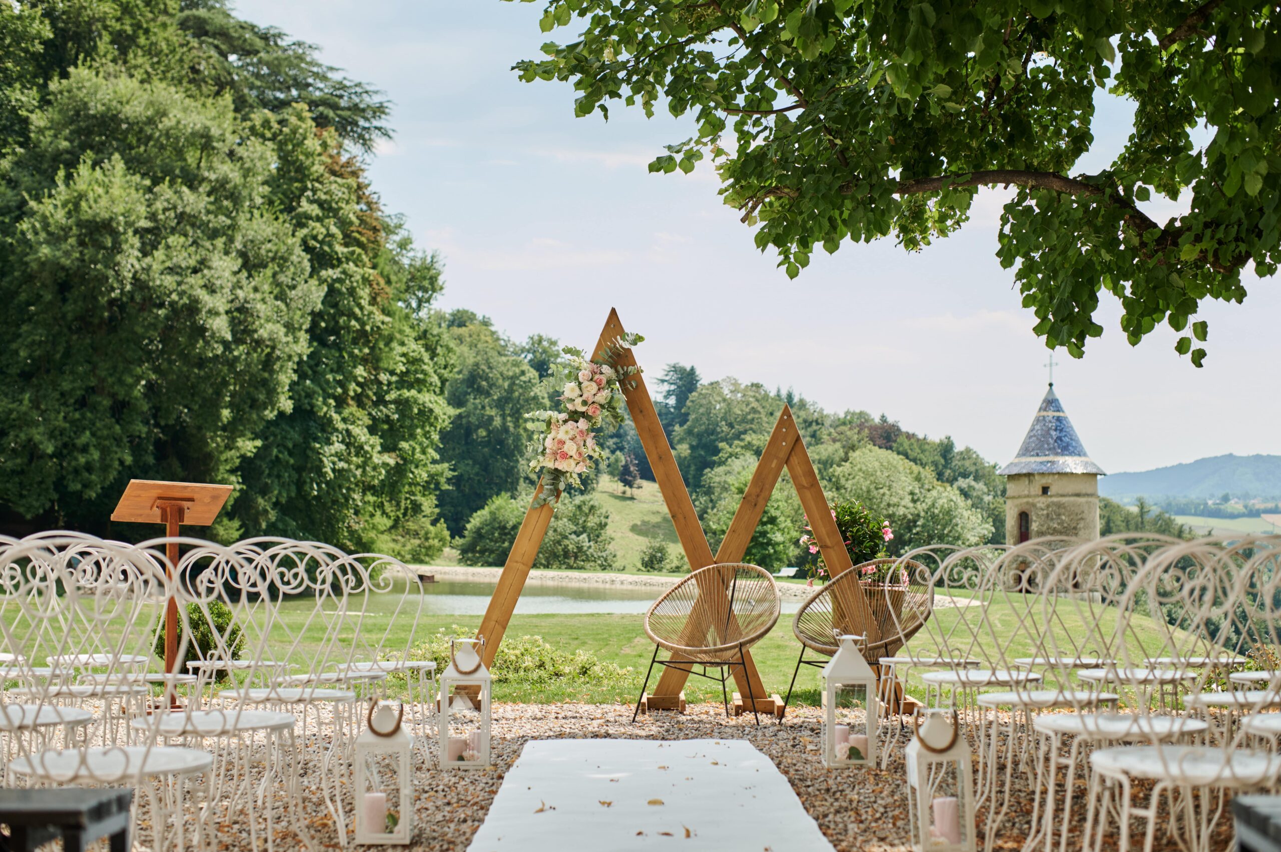 Photo cérémonie laïque avec une arche montagne en bois, des fauteils en corde pour les mariés et une allées blanches en tapis par Ma Déco Chic
